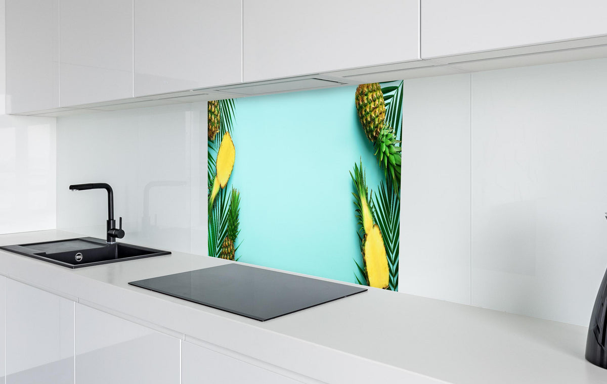 Spritzschutz - Ananas und tropische Palmenblätter in weißer Hochglanz-Küche hinter einem Cerankochfeld