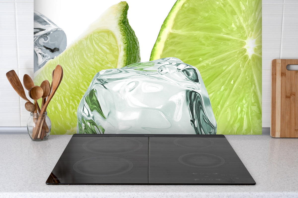 Spritzschutz - Eiswürfel mit saftiger Limette hinter einem Cerankochfeld zwischen Holz-Kochutensilien