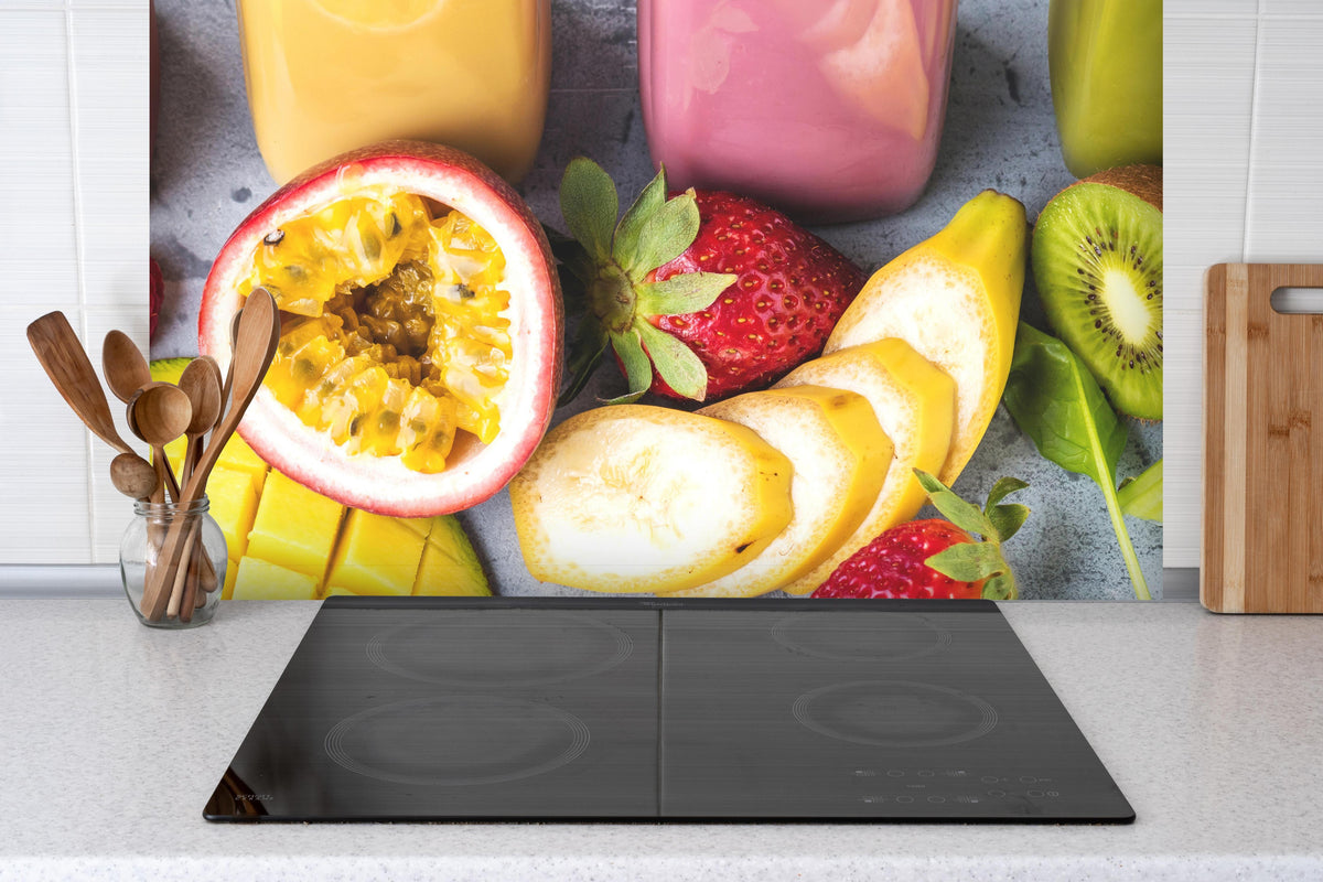 Spritzschutz - Smoothie aus Obst & Gemüse hinter einem Cerankochfeld zwischen Holz-Kochutensilien