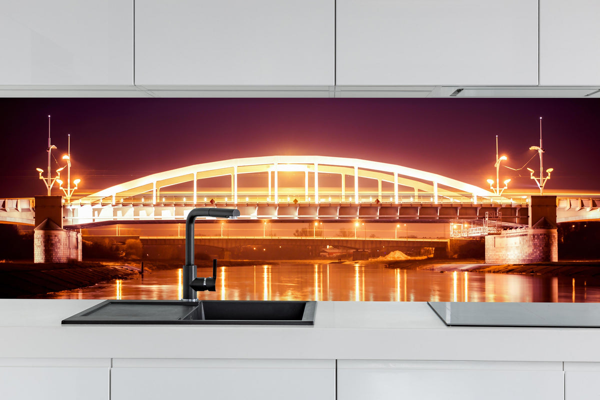 Küche - Nacht Blick auf eine Brücke über den Fluss Warta in Posen hinter weißen Hochglanz-Küchenregalen und schwarzem Wasserhahn
