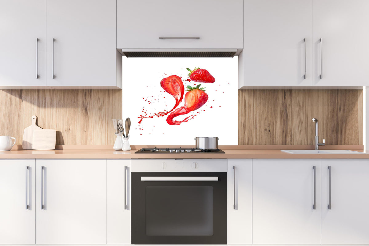 Spritzschutz - Aufgeschnittene Erdbeeren auf weißem Hintergrund hinter einem Cerankochfeld zwischen Holz-Kochutensilien

