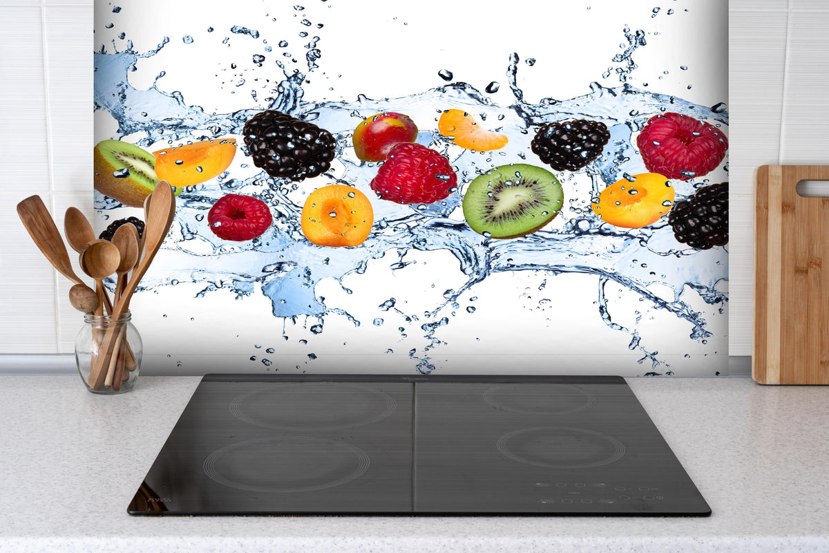 Spritzschutz - Buntes Fruchtwasser-Splash Fotografie hinter einem Cerankochfeld zwischen Holz-Kochutensilien
