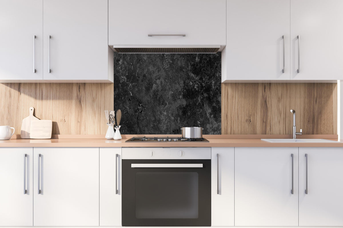 Spritzschutz - Dunkles Marmor Stein Design hinter einem Cerankochfeld zwischen Holz-Kochutensilien
