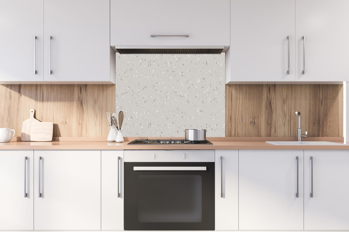 Spritzschutz - Graue Mosaiksteine  hinter einem Cerankochfeld zwischen Holz-Kochutensilien
