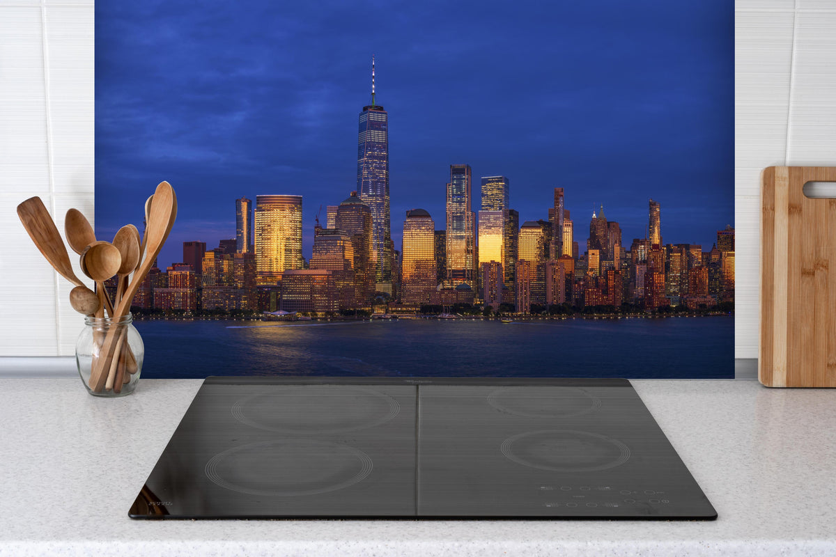 Spritzschutz - Blick auf die Skyline von Manhattan hinter einem Cerankochfeld zwischen Holz-Kochutensilien
