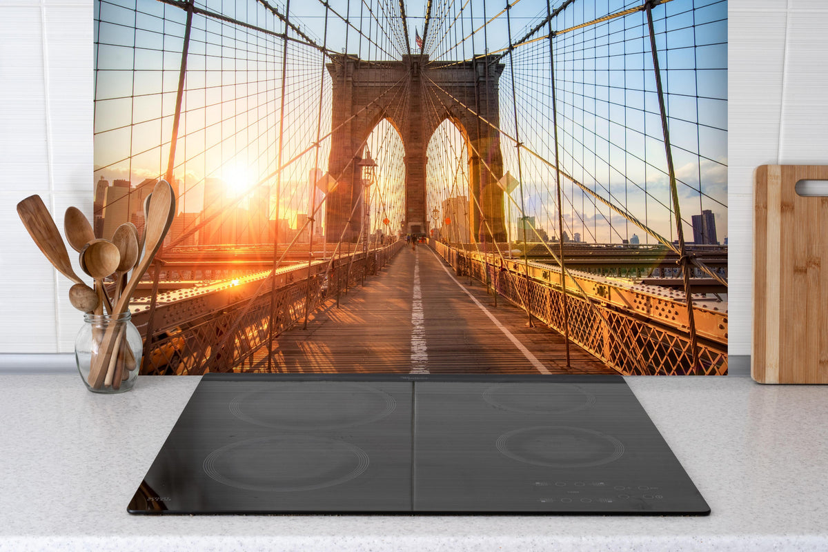 Spritzschutz - Brooklyn Bridge bei Sonnenuntergang  hinter einem Cerankochfeld zwischen Holz-Kochutensilien
