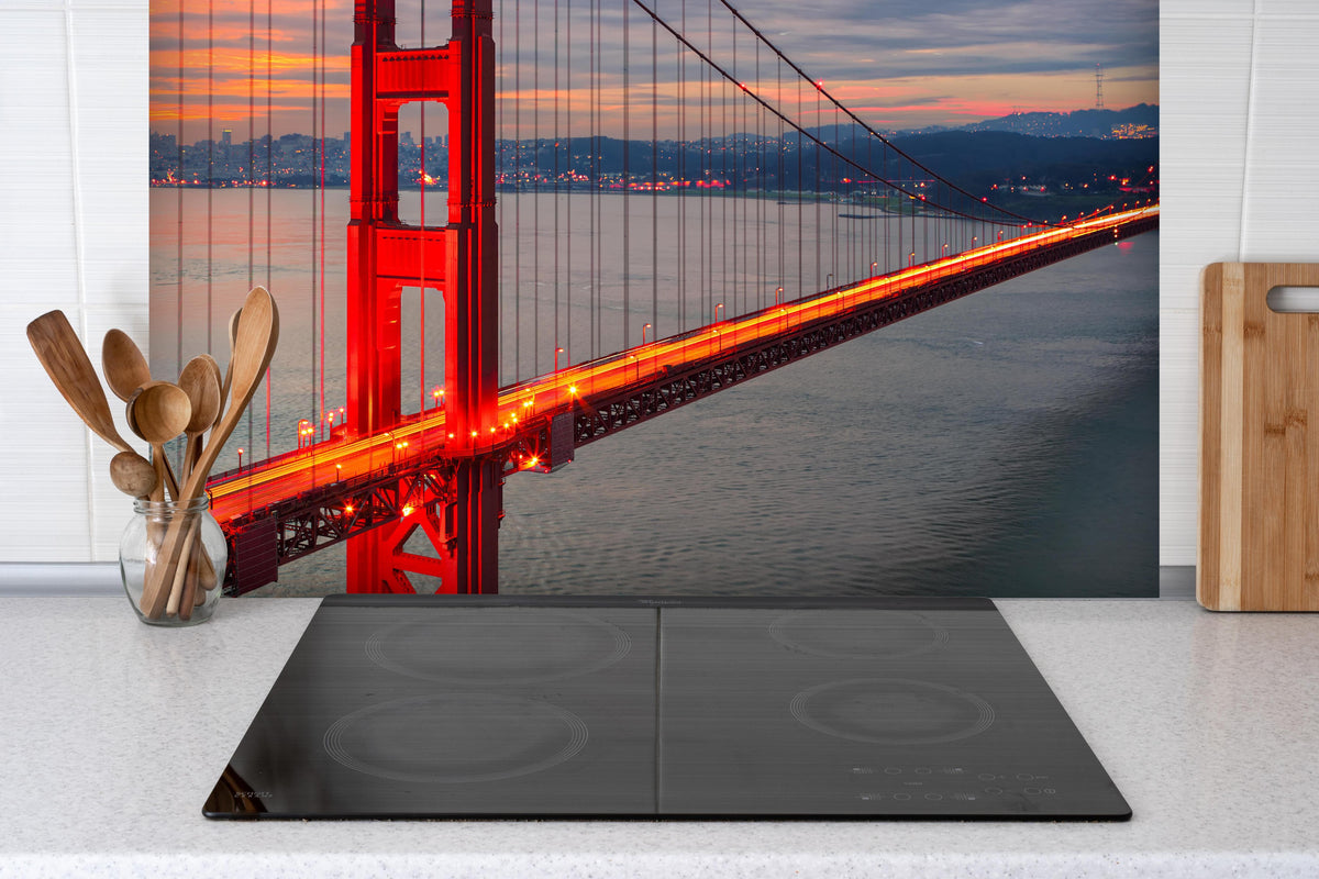 Spritzschutz - Die Golden Gate Bridge bei Sonnenaufgang hinter einem Cerankochfeld zwischen Holz-Kochutensilien
