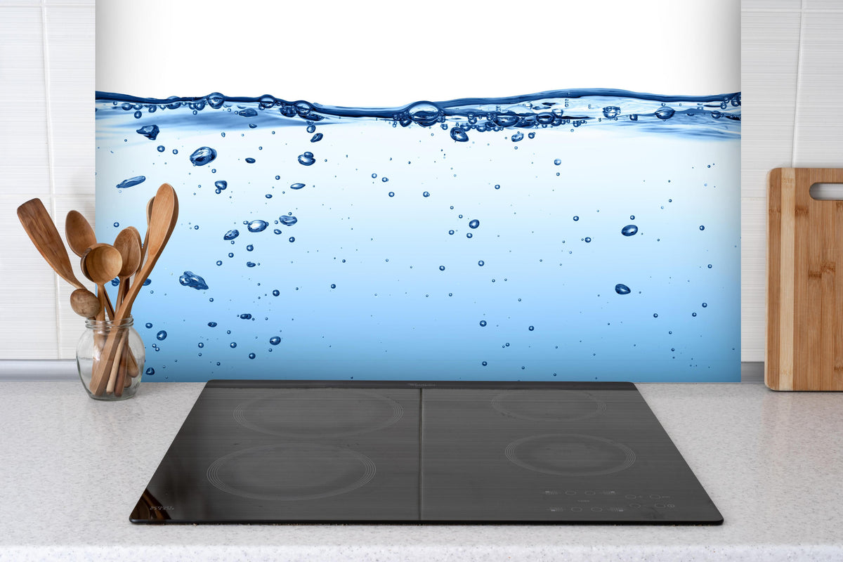 Spritzschutz - Energie des Wassers hinter einem Cerankochfeld zwischen Holz-Kochutensilien
