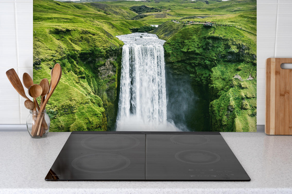 Spritzschutz - Isländischer Wasserfall Skogafoss hinter einem Cerankochfeld zwischen Holz-Kochutensilien
