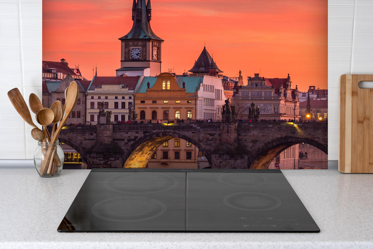 Spritzschutz - Karlsbrücke in Prag bei Sonnenuntergang  hinter einem Cerankochfeld zwischen Holz-Kochutensilien
