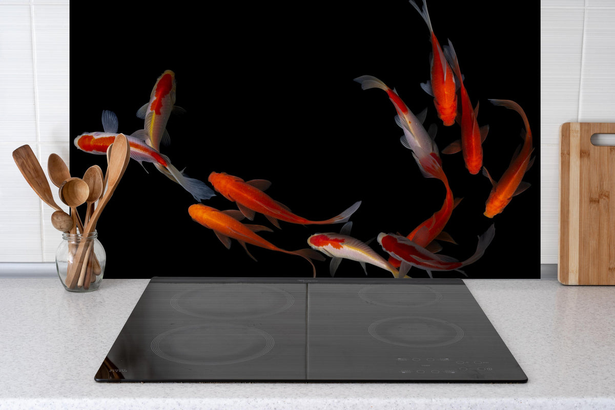 Spritzschutz - Koi Fische auf schwarzem Hintergrund hinter einem Cerankochfeld zwischen Holz-Kochutensilien
