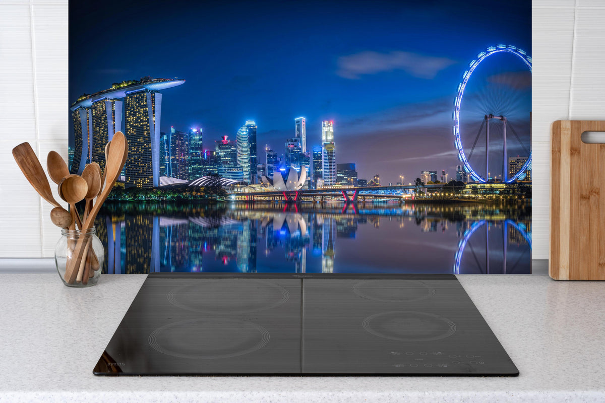 Spritzschutz - Skyline von Singapur und Blick auf den Wolkenkratzer hinter einem Cerankochfeld zwischen Holz-Kochutensilien
