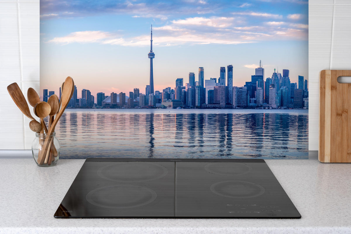 Spritzschutz - Skyline von Toronto hinter einem Cerankochfeld zwischen Holz-Kochutensilien
