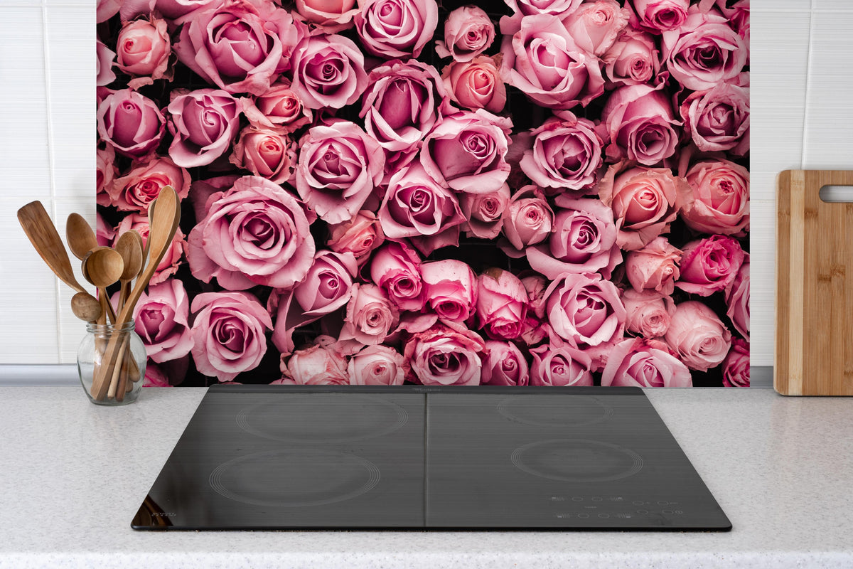 Spritzschutz - Wand aus frischen Rosen hinter einem Cerankochfeld zwischen Holz-Kochutensilien
