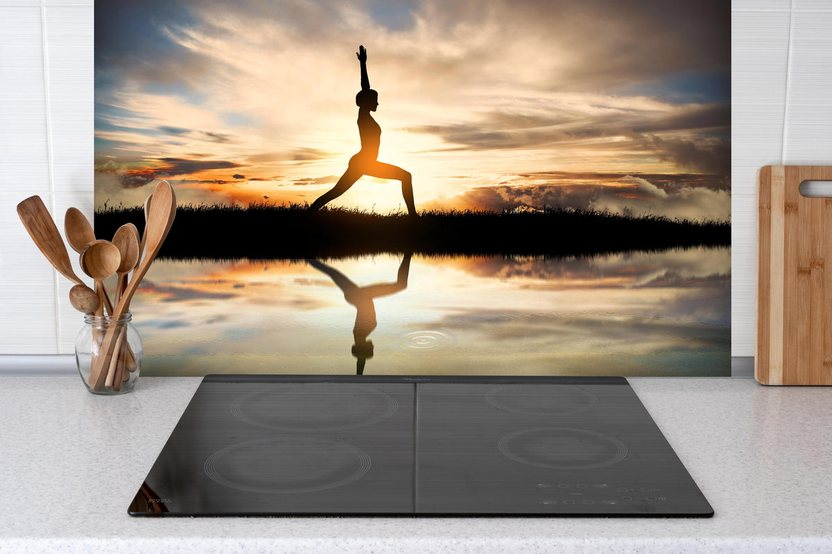 Spritzschutz - Yoga praktizierendes Mädchen hinter einem Cerankochfeld zwischen Holz-Kochutensilien
