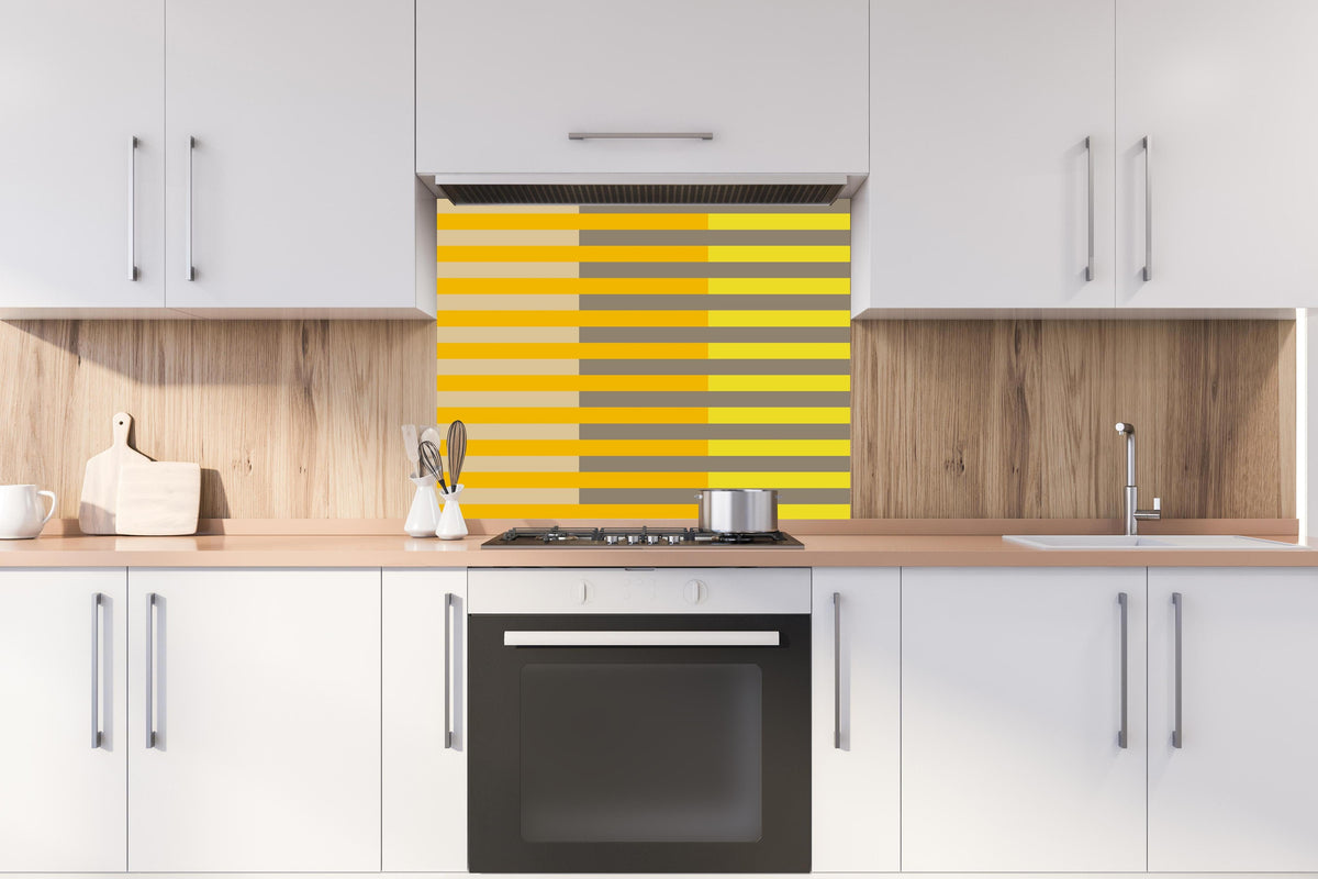 Spritzschutz - The Yellows - Multy Stripes - Honey hinter einem Cerankochfeld zwischen Holz-Kochutensilien
