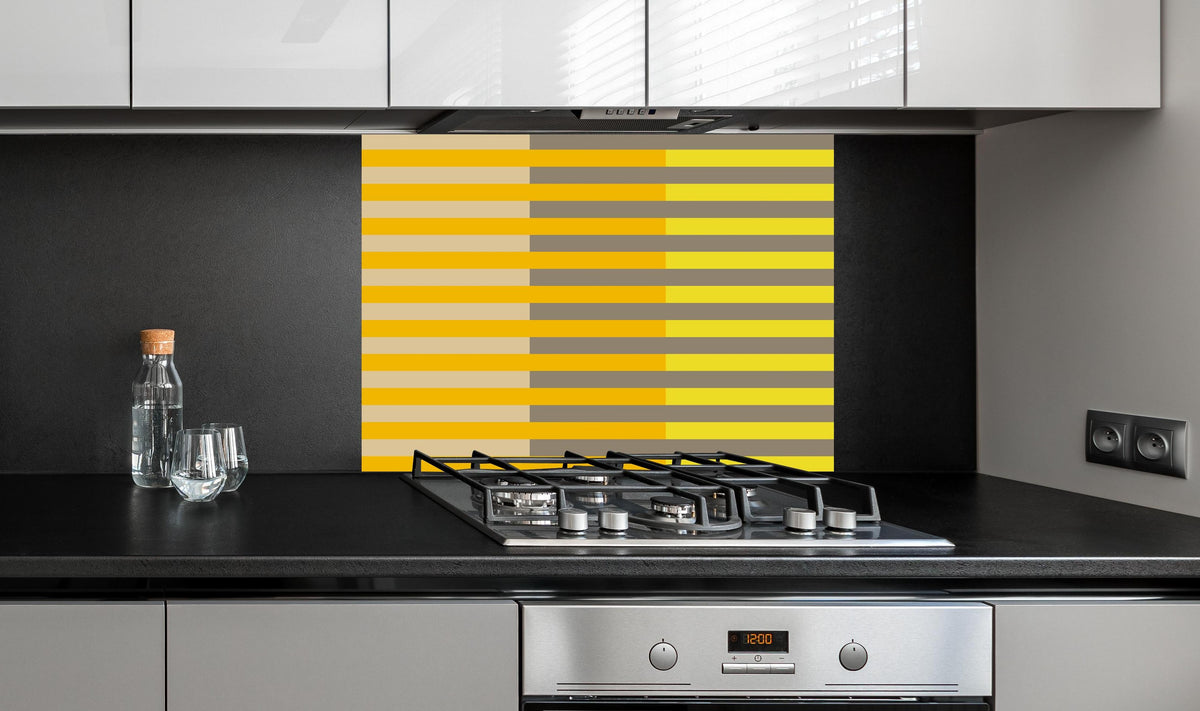 Spritzschutz - The Yellows - Multy Stripes - Honey hinter einem Cerankochfeld zwischen Holz-Kochutensilien

