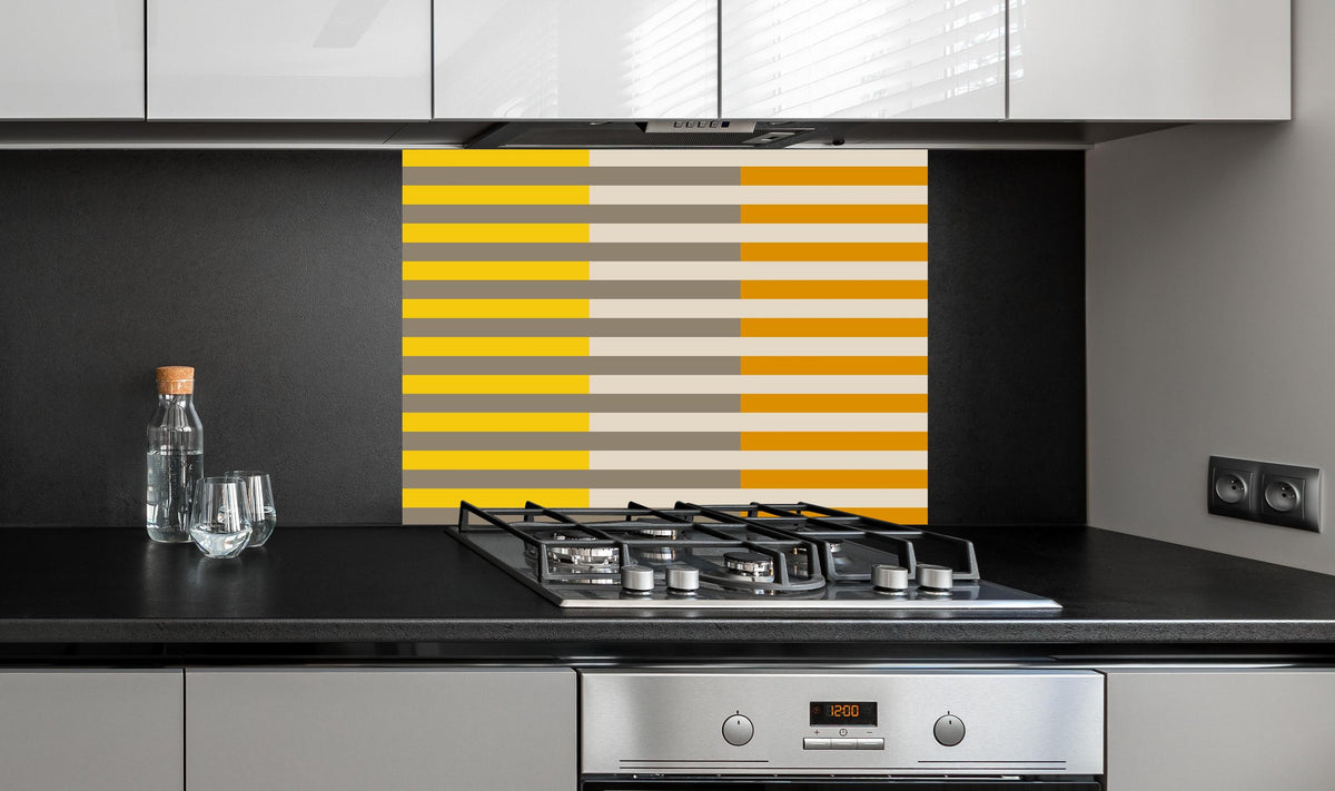 Spritzschutz - The Yellows - Multy Stripes - Saffron hinter einem Cerankochfeld zwischen Holz-Kochutensilien
