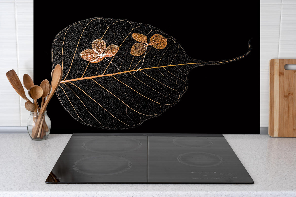 Spritzschutz - Trockene Blume im Detail hinter einem Cerankochfeld zwischen Holz-Kochutensilien
